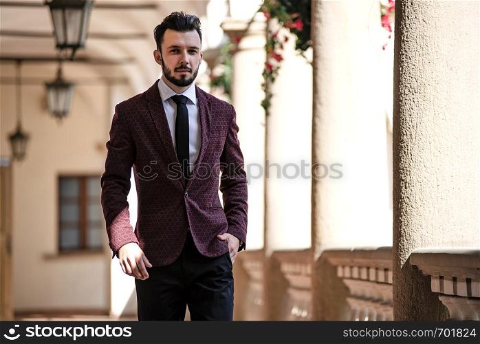 Elegant and fashionable businessman in jacket walking on the balcony of classical architecture building.
