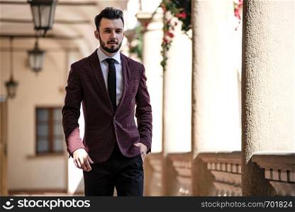 Elegant and fashionable businessman in jacket walking on the balcony of classical architecture building.