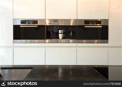 Elegant and modern white kitchen interior with oven and coffee machine close-up clean and luxury interior , induction. Elegant and modern white kitchen interior with oven and coffee machine close-up clean and luxury interior