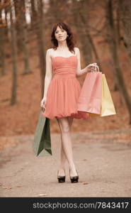 Elegant autumn shopper woman with sale bags outdoor in park after shopping. Vintage photo, sepia tone