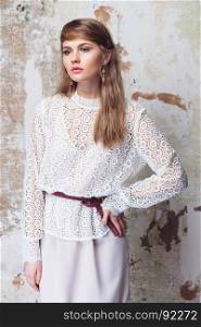 Elegant beautiful girl wearing white lace blouse posing on grunge background