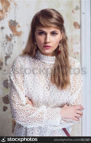 Elegant beautiful girl wearing white lace blouse posing on grunge background