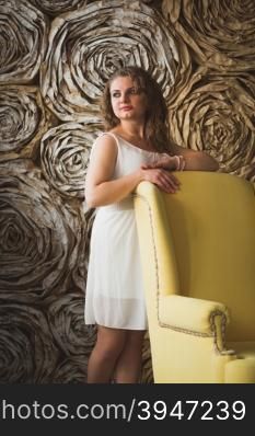 Elegant beautiful woman leaning on big yellow armchair