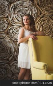 Elegant beautiful woman leaning on big yellow armchair