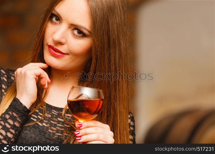 Elegant beauty lady long hair full make up wearing black dress tasting wine in rural cottage interior celler. Woman tasting wine in rural cottage interior