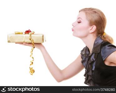 Elegant blond girl in black dress holding big golden christmas gift box with ribbon. Young woman blowing kiss. Holiday. Isolated on white. Studio shot.