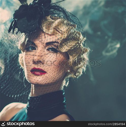 Elegant blond retro woman wearing little hat with veil in smoke
