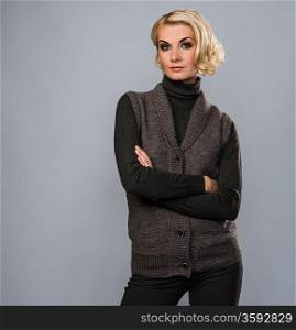 Elegant blond woman in casual brown clothes isolated on grey background