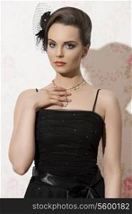 elegant brunette girl posing with black dress, necklace jewel and accessory in the hair-style