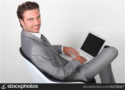 elegant businessman sitting in a chair and working on his laptop