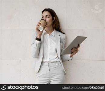 elegant businesswoman having coffee while holding tablet