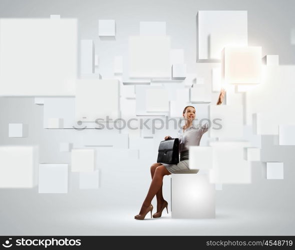 Elegant businesswoman. Image of elegant businesswoman sitting on white cube touching media button