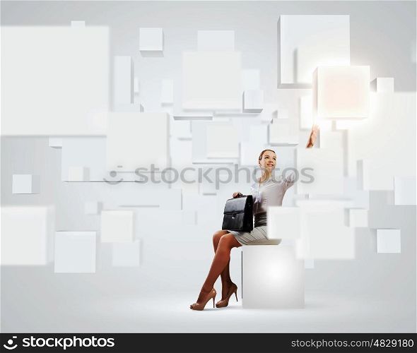 Elegant businesswoman. Image of elegant businesswoman sitting on white cube touching media button