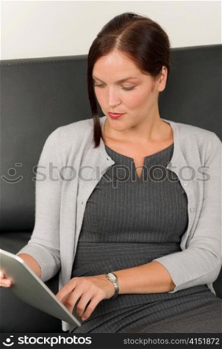 Elegant businesswoman on stylish leather sofa working touch tablet computer