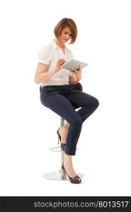 Elegant businesswoman sitting on chair and using pad. Studio shot, isolated.