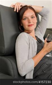 Elegant businesswoman sitting on leather sofa drink glass red wine