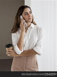 elegant businesswoman talking phone while holding coffee cup
