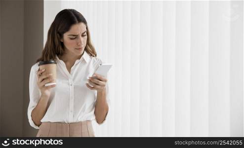 elegant businesswoman using smartphone while holding coffee cup with copy space