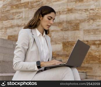 elegant businesswoman with smartwatch working laptop outdoors