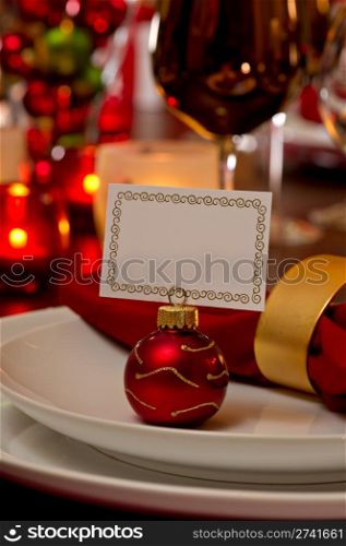 Elegant Christmas place setting place with ornament card holder on a white plate.