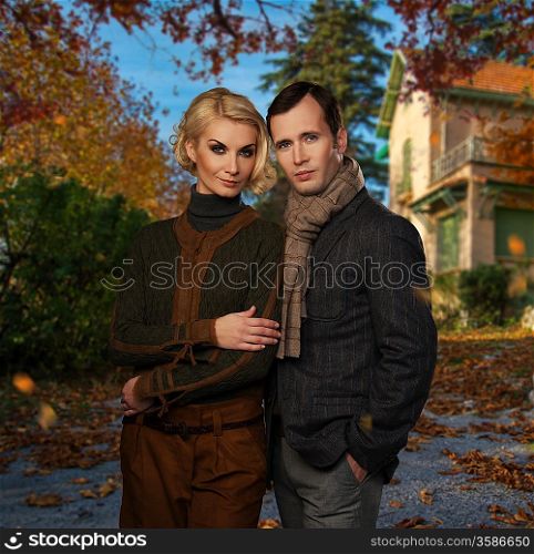 Elegant couple against country house on autumn day