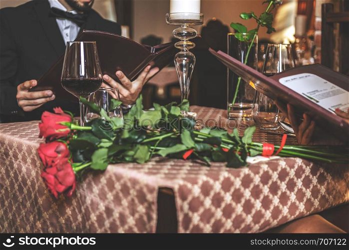 Elegant couple in love reading a menu during a romantic dinner in a restaurant in close-up (selective focus)