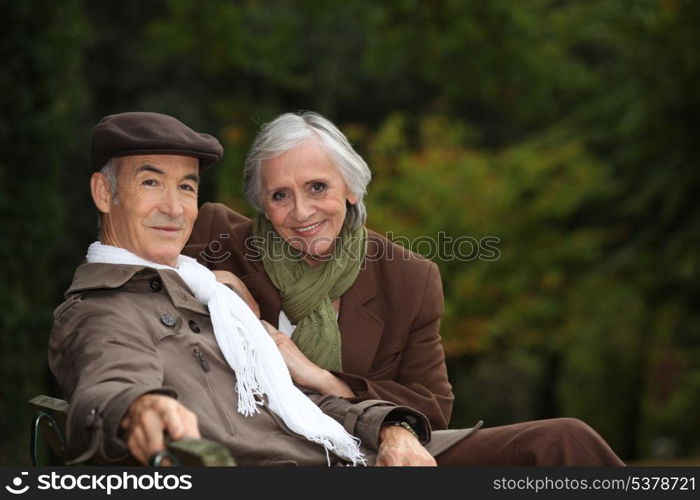 Elegant elderly couple sitting on a park bench