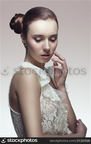 elegant fashion brunette woman posing with creative chignon hair-style and wearing sexy white lace shirt