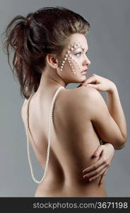 elegant fashion girl with creative make up showing her naked shoulder with a pearl necklace falling