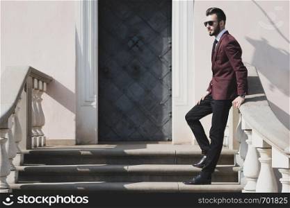 Elegant fashionable man in black sunglasses posing outdoor on the stairs (copy space).