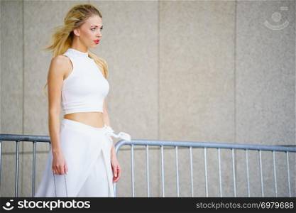 Elegant fashionable woman presenting trendy urban outfit. White crop top and trousers.. Woman wearing crop top and culottes