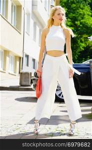 Elegant fashionable woman presenting trendy urban outfit. White crop top and trousers culottes.. Woman wearing crop top and culottes