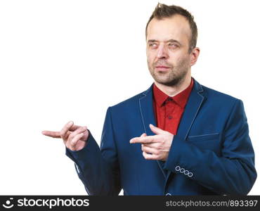 Elegant formal businessman wearing navy blue suit and red shirt pointing at copy space. Studio shot on isolated background.. Elegant man in suit pointing on copy space