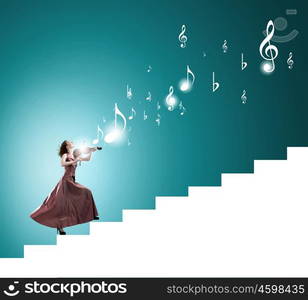 Elegant girl play violin. Young female violin player in long evening dress