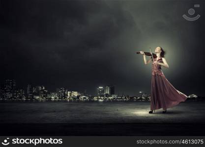 Elegant girl play violin. Young female violin player in long evening dress