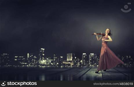 Elegant girl play violin. Young female violin player in long evening dress