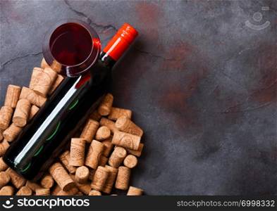 Elegant glass and bottle of red wine with corks on kitchen table background.