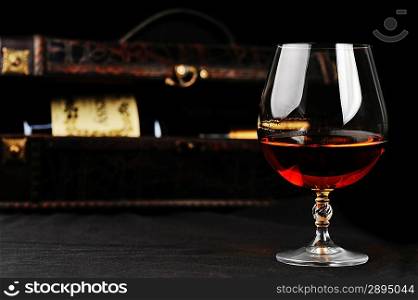 elegant glass of cognac and bottle in wooden case background