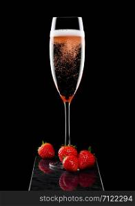 Elegant glass of pink rose champagne with strawberry and fresh berries on black marble board on black.