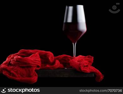 Elegant glass of red wine with red vintage on wooden board on black background.