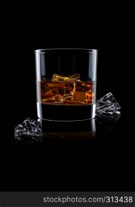 Elegant glass of whiskey with ice cubes on black background with reflection