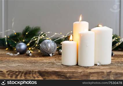 Elegant gray christmas scene with burning candles on natural wood background with bokeh lights. Elegant gray christmas