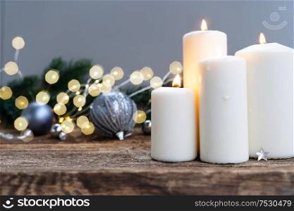 Elegant gray christmas scene with glowing candles on natural wood background with bokeh lights. Elegant gray christmas