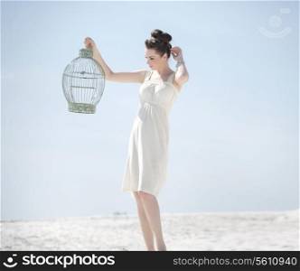 Elegant lady holding the golden bird cage
