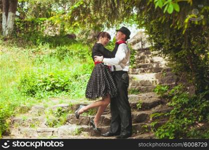 Elegant lady in red gloves and polka dot dresses and gentlman posing for photo. Retro fashion couple