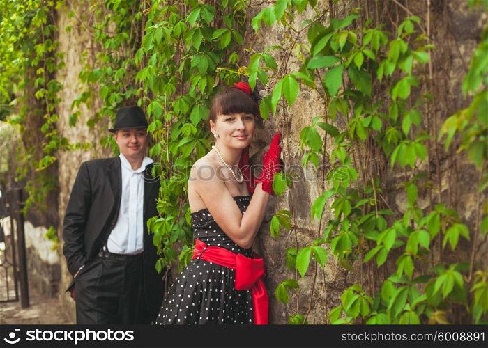 Elegant lady in red gloves and polka dot dresses and gentlman posing for photo. Retro fashion pair