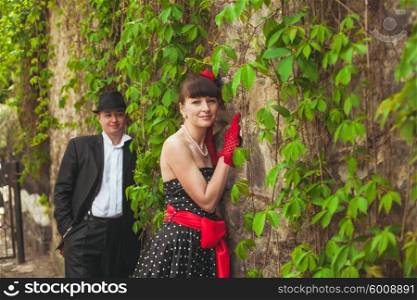 Elegant lady in red gloves and polka dot dresses and gentlman posing for photo. Retro fashion pair