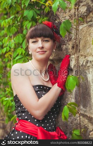 Elegant lady in red gloves and polka dot dresses posing for photo. Retro fashion woman