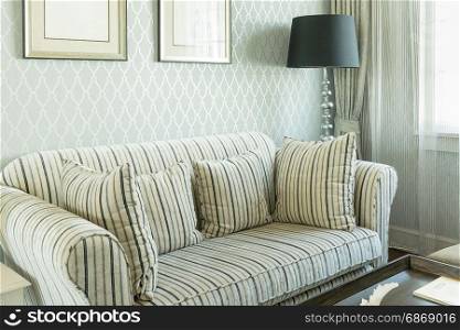 elegant living room interior with striped pattern pillows on sofa and decorative lamp