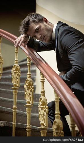 Elegant man leaing on a wooden handrail